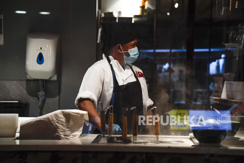 Seorang koki menggunakan masker ketika berada di dapur restoran. Selandia Baru jadi salah satu negara maju yang paling sukses mengendalikan pandemi. Ilustrasi.