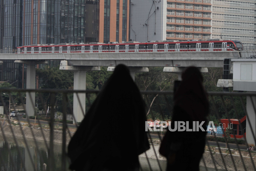 Warga melihat LRT melintas dari Jembatan penyeberangan multiguna (JPM) Dukuh Atas di Jakarta, Jumat (1/9/2023). 