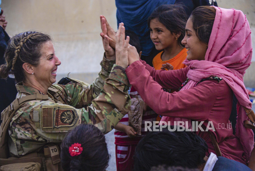  Dalam gambar yang disediakan oleh Marinir AS ini, seorang Penerbang AS dengan Joint Task Force-Crisis Response tos dengan seorang anak setelah membantu menyatukan kembali keluarga mereka di Bandara Internasional Hamid Karzai di Kabul, Afghanistan, Jumat, 20 Agustus 2021.