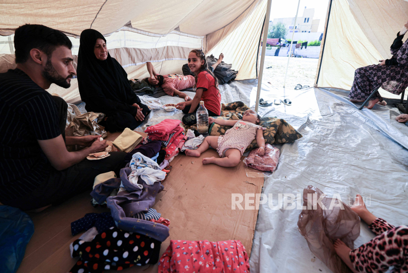 Keluarga duduk di dalam salah satu tenda yang didirikan untuk warga Palestina yang mencari perlindungan di halaman pusat Badan Bantuan dan Pekerjaan PBB untuk Pengungsi Palestina (UNRWA) di Khan Yunis di Jalur Gaza selatan pada Kamis (19/10/2023).