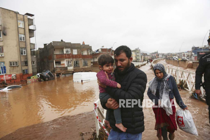 Warga berjalan meninggalkan tempat tinggalnya saat banjir setelah hujan lebat di Sanliurfa, Turki, Rabu, Rabu, (15/3/2023).  Hakan Akgun/DIA via AP