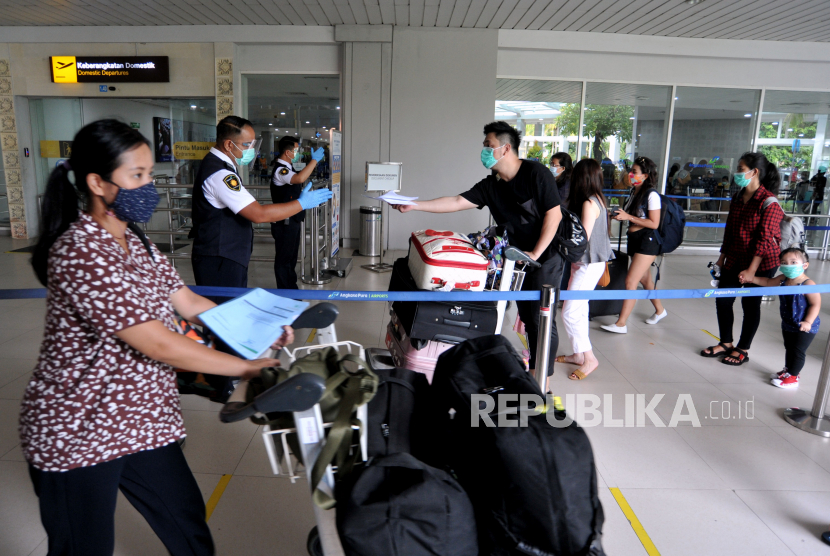 Petugas memeriksa tiket calon penumpang pesawat di Terminal Bandara Internasional I Gusti Ngurah Rai, Kabupaten Badung, Provinsi Bali, Ahad (3/1/2021).