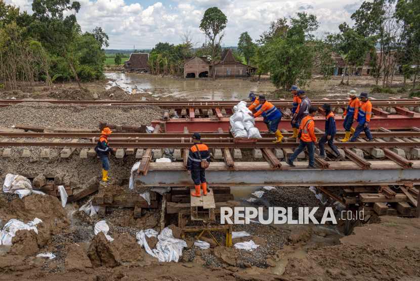 Sejumlah pekerja PT Kereta Api Indonesia (Persero) Daop 4 Semarang mendorong lori berisi batu balas untuk meterial perbaikan jalur rel KA km 32+6/7 antara Stasiun Gubug - Karangjati yang sempat ditutup karena banjir luapan air Sungai Tuntang di Gubug, Kabupaten Grobogan Jawa Tengah, Ahad (9/3/2025). Jalur KA yang sempat ditutup sejak pukul 05:27 WIB akibat banjir itu pada pukul 12:08 WIB sudah bisa dilintasi KA Barang Peti Kemas No. 2529 relasi Surabaya–Jakarta, disusul KA No. 1 Argo Bromo Anggrek pada pukul 12.08 WIB dengan kecepatan terbatas. 