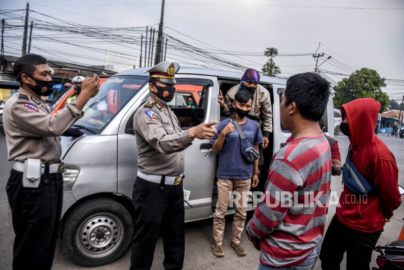 Petugas kepolisian memeriksa identitas dan surat keterangan negatif Covid-19 dari pengemudi dan penumpang kendaraan dengan pelat nomor dari luar Bandung di gerbang Tol Padalarang, Kabupaten Bandung Barat, Senin (3/5). Penyekatan yang dilakukan oleh petugas gabungan dari Polisi, TNI, Dishub dan Satpol PP tersebut merupakan bagian dari pelaksanaan larangan mudik Hari Raya Idul Fitri 1442 H yang berlaku pada 6-17 Mei 2021. Foto: Republika/Abdan Syakura