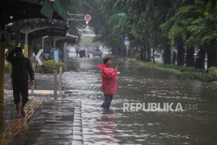 Warga berjalan melewati genangan air di Jalan Letjen Suprapto, Cempaka Putih, Jakarta, Kamis (29/2/2024). Hujan deras yang mengguyur Jakarta sejak dini hari dan buruknya drainase membuat ruas jalur lambat pada jalan tersebut tergenang air.
