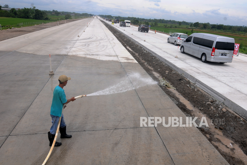 Pekerja menyemprotkan air pada jalan tol fungsional Solo-Yogyakarta di Banyudono, Boyolali, Jawa Tengah, Kamis (13/4/2023). 