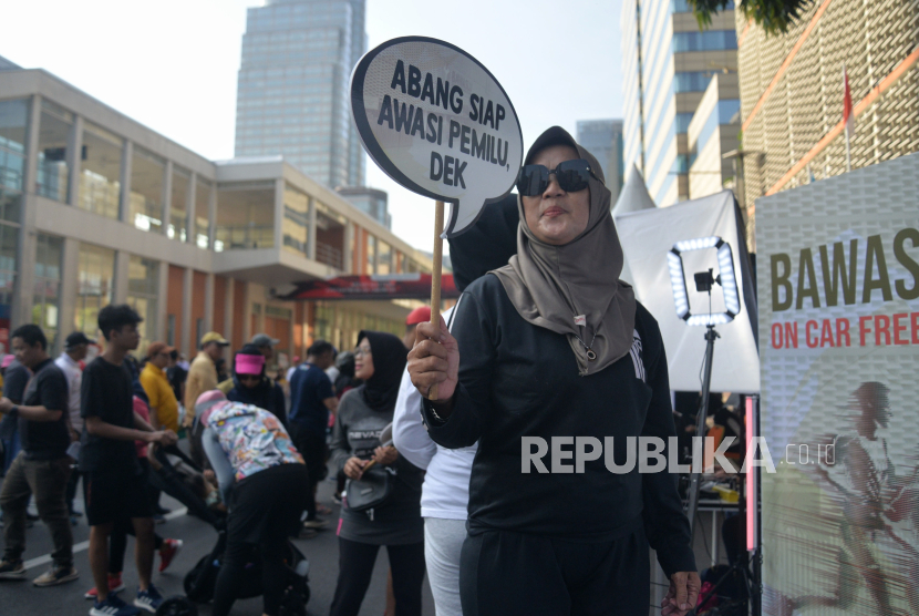 Warga berpose dengan memegang poster sosialisasi pengawasan pemilu saat acara Bawaslu on Car Free Day di depan kantor Bawaslu, Jakarta, Ahad (17/12/2023). Kegiatan tersebut dalam rangka  mengajak warga untuk ikut berpartisipasi mengawasi pemilu  sehingga terciptanya pemilu 2024 yang bersih dan damai.