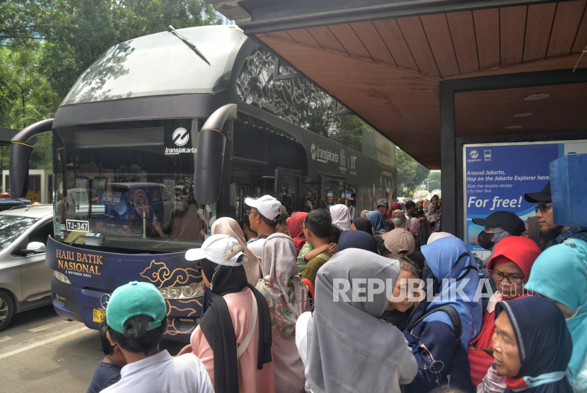 Warga mengantre untuk menaiki Bus Wisata Transjakarta di Kawasan Monas, Jakarta, Senin (1/1/2024). Fasilitas bus tingkat wisata Transjakarta ini masih diminati warga untuk mengisi liburan tahun baru. Bus tingkat gratis itu memungkinkan warga menikmati pemandangan lanskap gedung-gedung perkantoran di Ibu Kota. Banyak dari warga yang menganjak anak-anak.