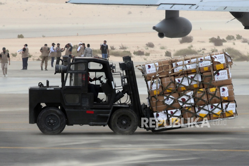 Relawan dari organisasi kemanusiaan Qatar dan Bulan Sabit Merah Mesir membongkar bantuan yang ditujukan untuk warga Palestina di Jalur Gaza di bandara Arish Mesir di utara Sinai, Mesir, Ahad (19/11/2023). 