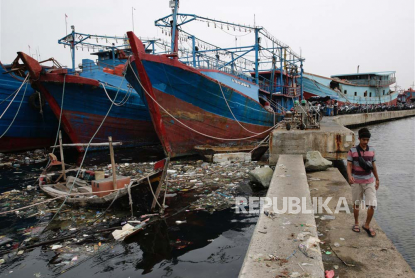 Seorang warga berjalan melewati perairan Jakarta yang penuh dengan sampah, terutama sampah plastik, di pelabuhan tradisional Muara Baru di Jakarta, Kamis (18/5/2023).  Pemerintah Indonesia menetapkan tujuan pada tahun 2019, berharap dapat menghilangkan sampah laut hingga 70 persen pada tahun 2025.