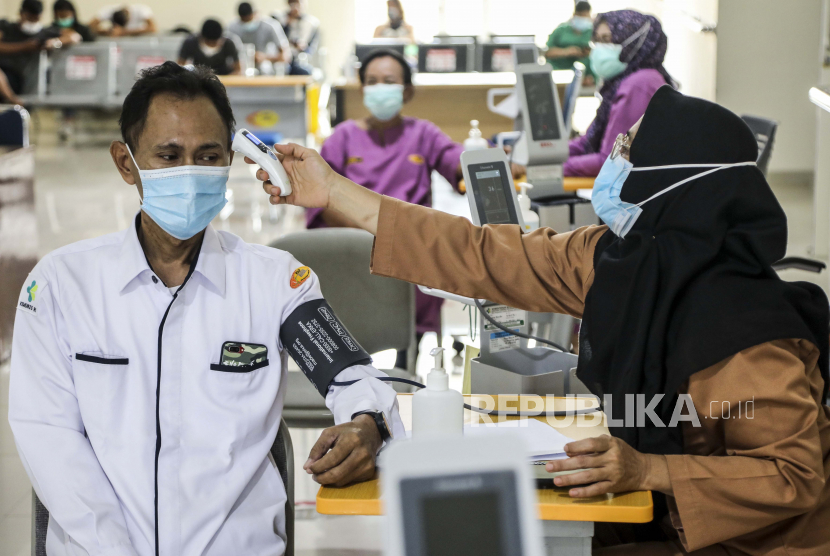  Seorang petugas kesehatan memeriksa suhu tubuh seorang pria selama kampanye vaksinasi COVID-19 di Medan, Sumatera Utara, Indonesia (ilustrasi)