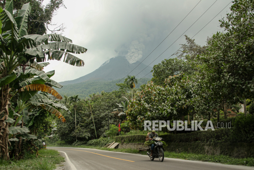 Warga mengendarai sepeda motor berlatar belakang Gunung Lewotobi Laki-Laki yang erupsi di Kecamatan Wulanggitang, Kabupaten Flores Timur, NTT, Sabtu (6/1/2024). Pos Pemantau Gunung Api (PGA) Laki-Laki mencatat Gunung Lewotobi kembali erupsi pada Sabtu 6 Januari pagi dengan asap kawah bertekanan sedang hingga kuat yang teramati berwarna putih dan kelabu dengan intensitas tebal dan tinggi 1.000-1.500 meter di atas puncak kawah. 