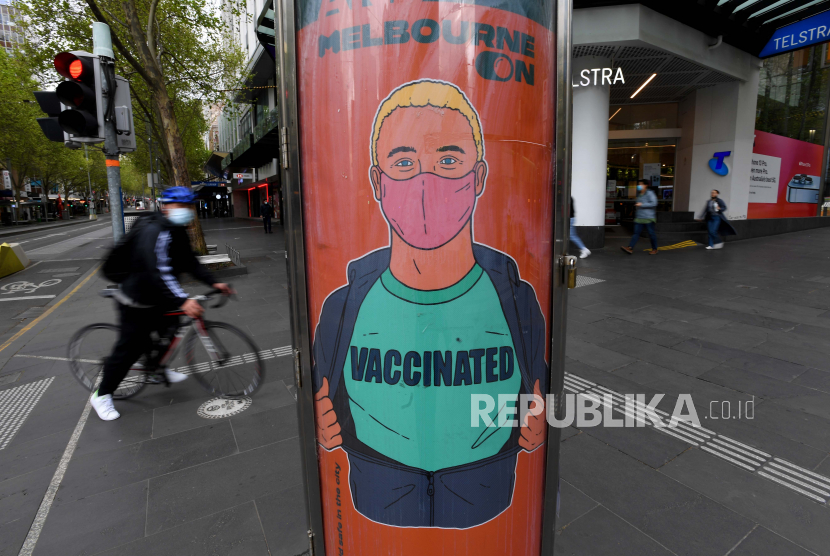 Seorang mengendarai sepeda melewati iklan yang mempromosikan vaksinasi COVID-19 menjelang rapat umum yang direncanakan menentang vaksinasi COVID-19 wajib di Melbourne, Victoria, Australia, 24 September 2021.
