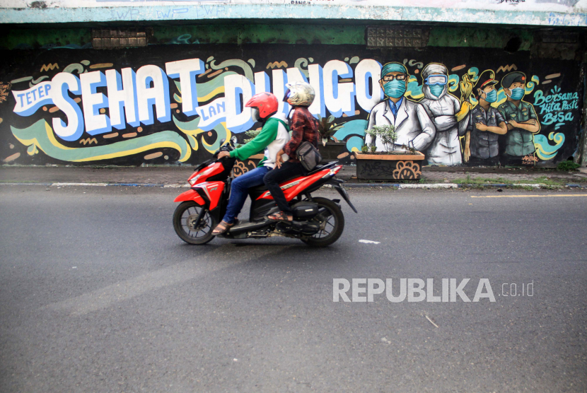 Pengendara melintas di depan mural tentang pandemi Covid-19 di Bangil, Pasuruan, Sidoarjo, Jawa Timur, Senin (20/4/2020). Mural tersebut dibuat bertujuan untuk mensosialisasikan dan mengedukasi warga agar tetap waspada terhadap potensi penyebaran virus corona atau COVID-19