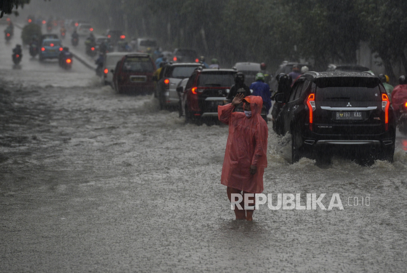 Petugas PPSU mengatur lalu lintas kendaraan untuk menghindari genangan air di kawasan Tanjung Barat, Jakarta.