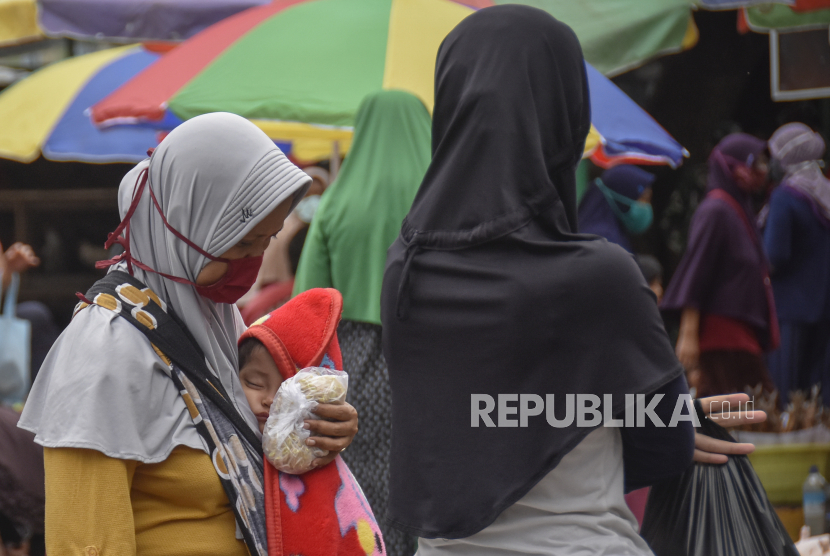 Seorang perempuan menggendong bayinya saat berbelanja di pasar tradisional Kebon Roek, Ampenan, Mataram, NTB, Kamis (28/5/2020). Menurut data Dinas Kesehatan Provinsi NTB per 26 Mei 2020, jumlah anak-anak di NTB yang positif tertular COVID-19 sebanyak 86 orang dengan rincian 35 balita (usia 0-5 tahun) dan 51 anak (usia 6-18 tahun) yang sebagian besar tertular dari keluarga dekat