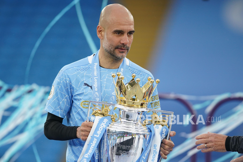 Manajer Manchester City Pep Guardiola merayakan dengan trofi setelah memenangkan Liga Premier Inggris, Ahad (23/5). 