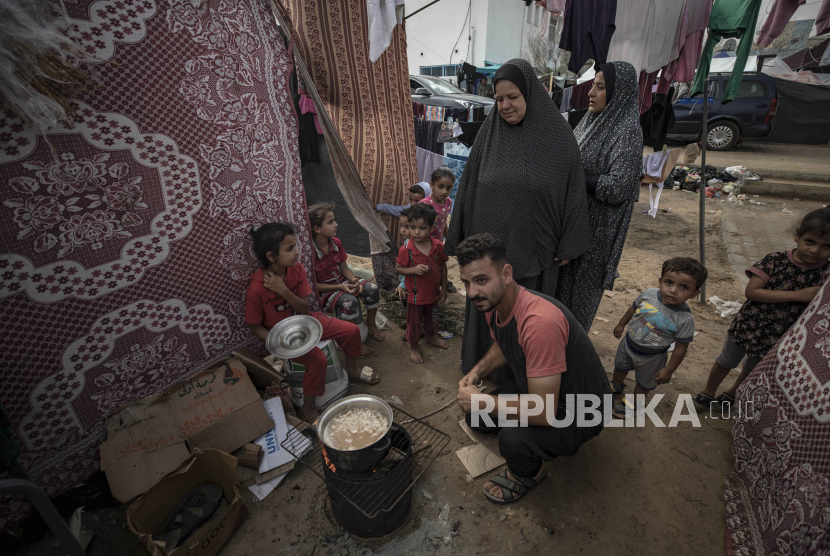 Orang-orang memasak makanan di dalam kompleks tenda di tenda kamp untuk pengungsi Palestina di Khan Yunis, 29 Oktober 2023.