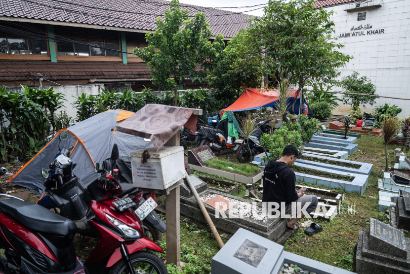 Warga korban banjir beristirahat di tenda di pemakaman umum, Pejaten Timur, Jakarta, Selasa (4/3/2025). Warga mendirikan tenda untuk mengungsi di tempat pemakaman umum (TPU) kawasan Pejaten Timur, Jakarta Selatan untuk sementara waktu karena tempat tinggalnya terendam banjir. 