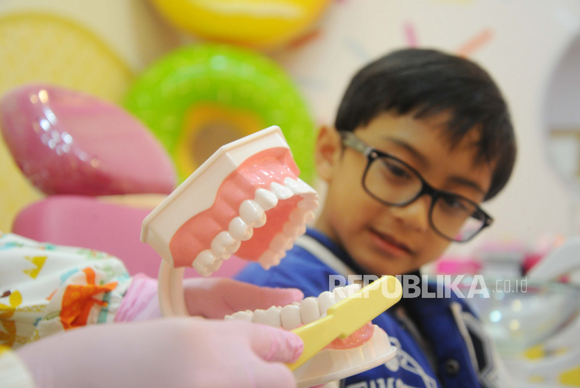 Dokter sedang menjelaskan perawatan gigi kepada anak (Ilustrasi). Agar anak tak takut ke dokter gigi, mereka perlu mendapatkan pengalaman dan pemahaman.