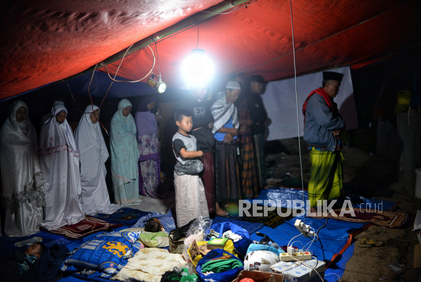 Sejumlah pengungsi melaksanakan salat isya di Kampung Gasol II, Desa Gasol, Cugenang, Kabupaten Cianjur, Jawa Barat, Kamis (24/11/2022).Berdasarkan data dari BNPB, hingga hari Kamis (24/11/2022) jumlah pengungsi akibat gempa di Cianjur mencapai 62.545 orang. Republika/Thoudy Badai