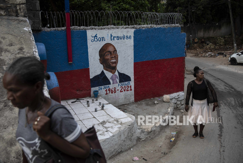 Wanita berjalan di sebelah mural dengan potret presiden Haiti Jovenel Moïse yang terbunuh di Port-au-Prince, Haiti, Rabu, 22 September 2021.
