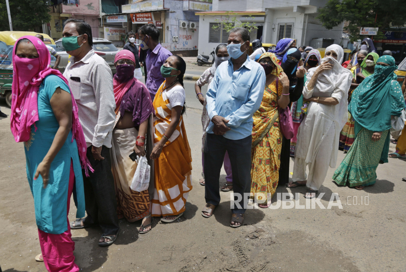  Orang India yang memakai masker sebagai tindakan pencegahan terhadap corona virus berdiri dalam antrean di luar sebuah bank di Ahmedabad, India, Senin, 20 Juli 2020. Negara dengan 1,4 miliar orang ini memiliki jumlah kasus virus corona terbanyak ketiga di dunia.