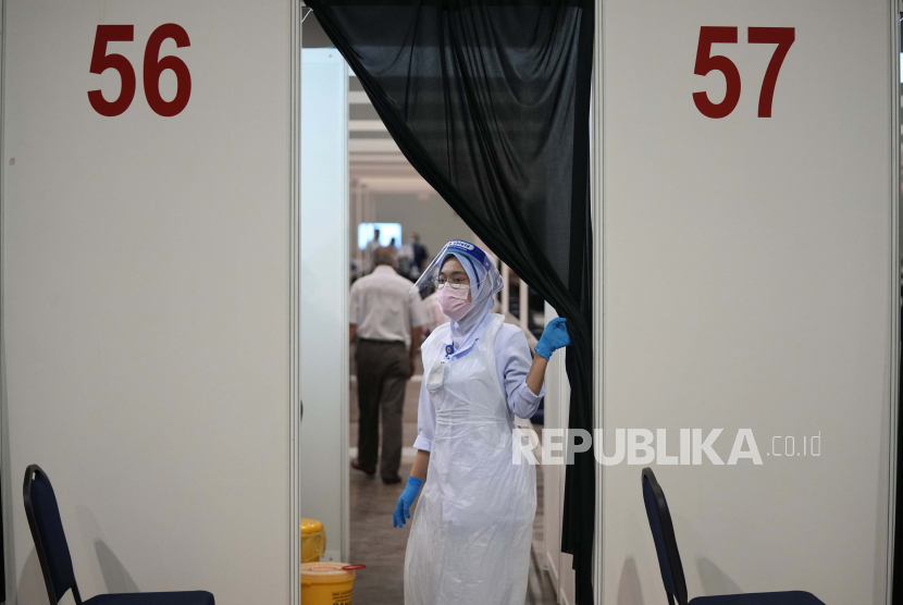  Seorang staf kesehatan melihat keluar dari sepatu bot vaksinasi untuk penyakit coronavirus (COVID-19) di pusat vaksinasi di Kuala Lumpur, Malaysia, Senin, 31 Mei 2021. 