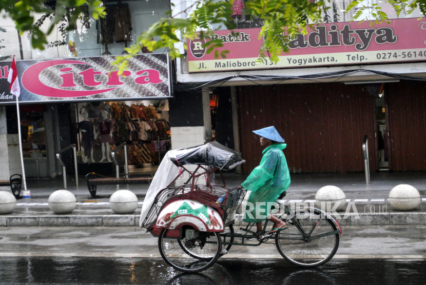 Becak kayuh menggunakan jas hujan melintas di kawasan Malioboro, Yogyakarta, Selasa (11/8). Masyarakat dihimbau mewaspadai cuaca ekstrem. Perubahan cuaca yang cepat terjadi dari panas ke hujan dan disertai angin kencang. Meski musim kemarau masih bisa terjadi penghujan.