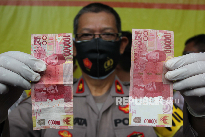 Polisi menunjukan barang bukti uang palsu (kanan) dan uang asli (kiri) 