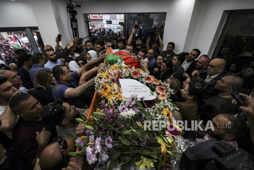 Warga Palestina mengepung jenazah jurnalis veteran Al-Jazeera Shireen Abu Akleh yang terbungkus bendera Palestina, saat dibawa ke kantor saluran berita di kota Ramallah, Tepi Barat, Rabu, 11 Mei 2022. 