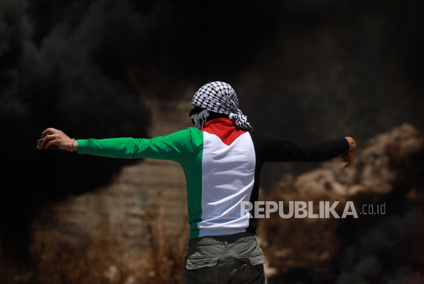 Seorang pria mengenakan keffiyeh untuk menutupi wajahnya. Di Palestina, keffiyeh berwarna hitam putih terutama dipakai untuk tujuan perlawanan dan solidaritas.