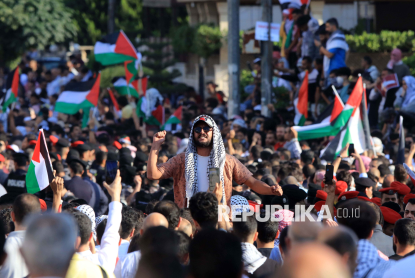 Pengunjuk rasa mengibarkan bendera Palestina menyusul serangan terhadap sebuah rumah sakit di Jalur Gaza, dalam aksi di dekat kedutaan Israel di Amman, Yordania, pada Oktober 2023.