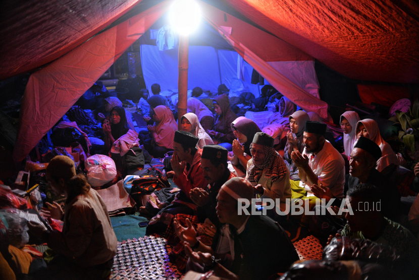 Pengungsi berdoa di dalam tenda darurat di Kampung Gasol, Desa Gasol, Cugenang, Kabupaten Cianjur, Jawa Barat. Beberapa pengungsi korban gempa Cianjur mengisi waktu malam hari di tenda pengungsian dengan menggelar tahlil atau menyaksikan pertandingan piala dunia. Republika/Thoudy Badai