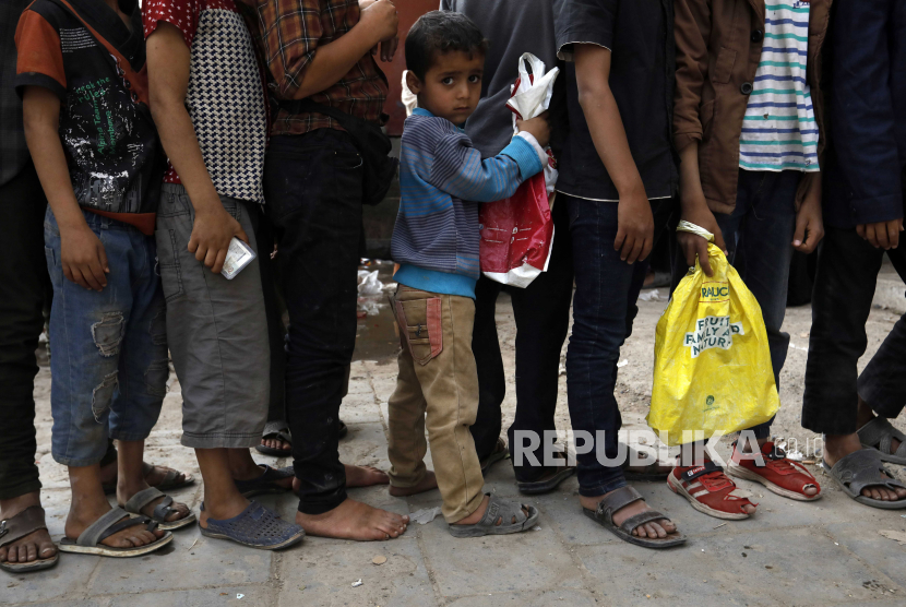 Tiga Juta Anak Yaman Kehilangan Akses Pendidikan. Seorang anak Yaman (tengah) berdiri antara lain menunggu bantuan makanan keluarganya untuk berbuka puasa, makanan yang secara tradisional diambil setelah salat magrib untuk berbuka puasa harian Ramadhan, selama bulan puasa Ramadhan di Sana
