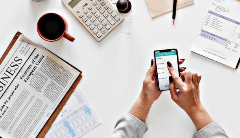 Seseorang memegang smartphone guna melakukan pencatatan dan perencanaan keuangan. (Unsplash/Rawpixel)