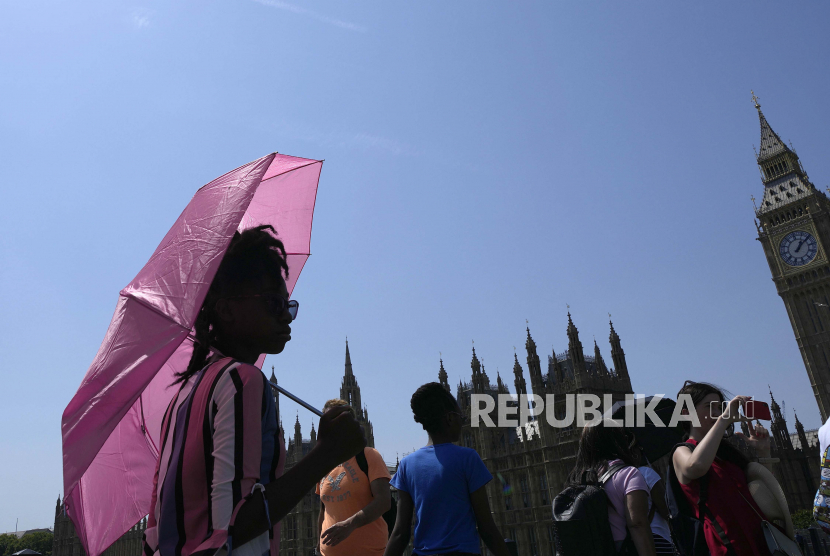Seorang wanita berlindung dari matahari dengan payung saat dia berjalan menyusuri Jembatan Westminster di London, Selasa, 19 Juli 2022. Studi menyatakan sebagian besar bagian dunia akan berada dalam cengkeraman panas ekstrem pada 2100. Ilustrasi.
