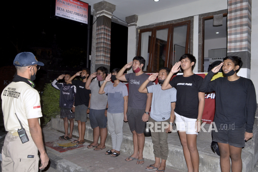 Sejumlah remaja menyanyikan lagu Indonesia Raya sebagai upaya pembinaan saat terjaring razia aksi balap liar di wilayah Desa Adat Jimbaran, Badung.