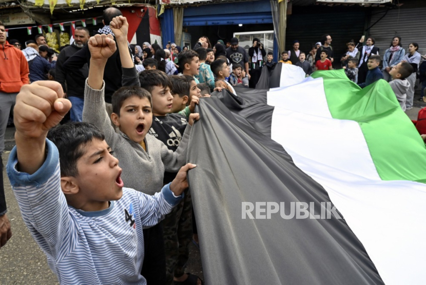 Warga Palestina yang tinggal di Lebanon meneriakkan slogan sambil membawa bendera Palestina saat pemogokan umum, menuntut gencatan senjata di Gaza, di kamp pengungsi Burj al-Barajneh, (11/12/2023). 