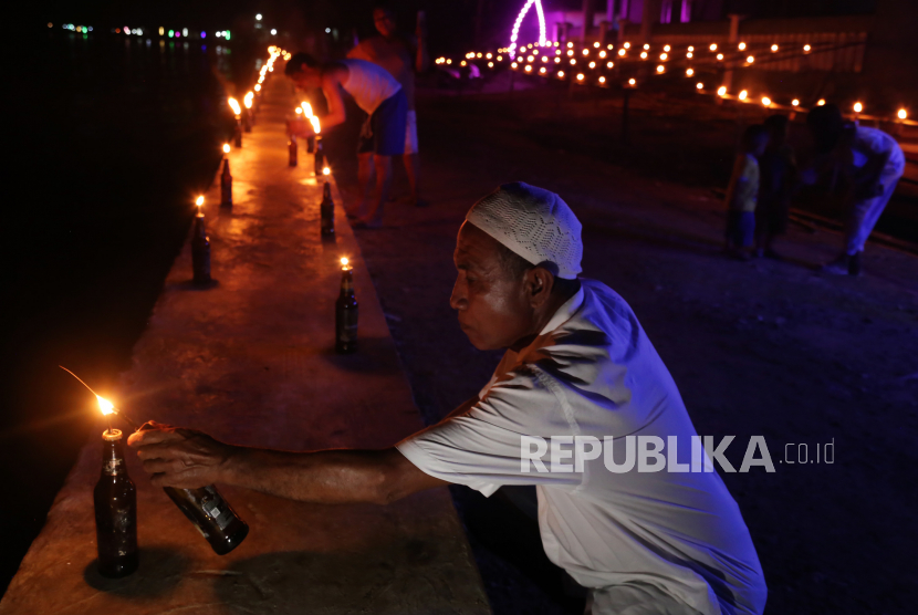 Seorang warga menyalakan lampu pelita saat merayakan tradisi malam Lailatul Qadar atau malam ela-ela di Desa Amasing Kota,Pulau Bacan, Kabupaten Halmahera Selatan, Maluku Utara, Selasa (18/4/2023). 