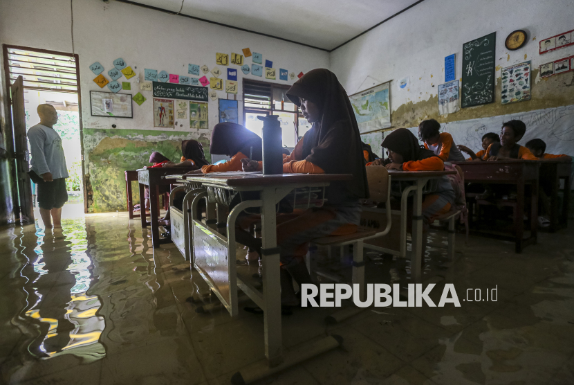 Potret Siswa SDN Eretan Serang Belajar di Ruang Kelas yang Terendam Banjir