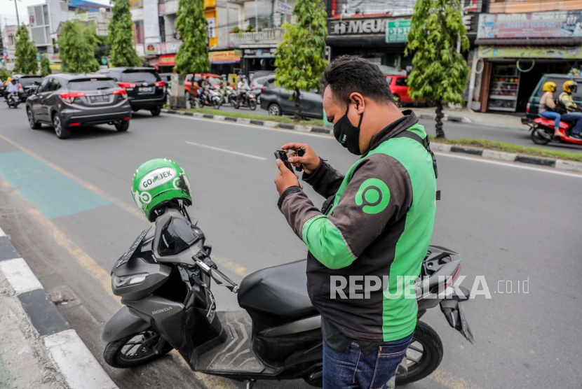 Seorang pengemudi Gojek memeriksa ponselnya saat ia berhenti di pinggir jalan di Medan, Sumatra Utara, Selasa (18/5). Perusahaan tumpangan Gojek dan perusahaan e-commerce Tokopedia telah mengumumkan merger dan membentuk perusahaan bernilai miliaran dolar, GoTo Group .