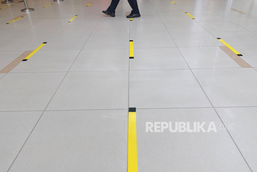Karyawan PT Angkasa Pura II (Persero) melintas di lantai yang telah diberi stiker panduan jarak, di Bandara Depati Amir, Kota Pangkalpinang, Kepulauan Bangka Belitung, Kamis (19/3/2020).