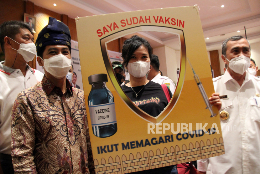 Seorang relawan foto bersama dengan Wakil Menteri Kesehatan Dante Saksono Harbuwono (kiri) dan Gubernur Riau Syamsuar (kanan) saat vaksinasi COVID-19 secara massal di Pekanbaru, Riau, Rabu (24/3/2021). Vaksinasi tersebut berlangsung selama empat hari hingga 26 Maret 2021  dengan target sebanyak 5.000 orang penerima vaksin. 