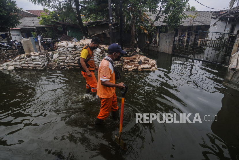 Petugas berjalan melewati banjir di kawasan Duren Sawit, Jakarta, Selasa (15/3/2022). Wagub Ahmad Riza Patria mengklaim hampir tak ada banjir di Jakarta hingga April.