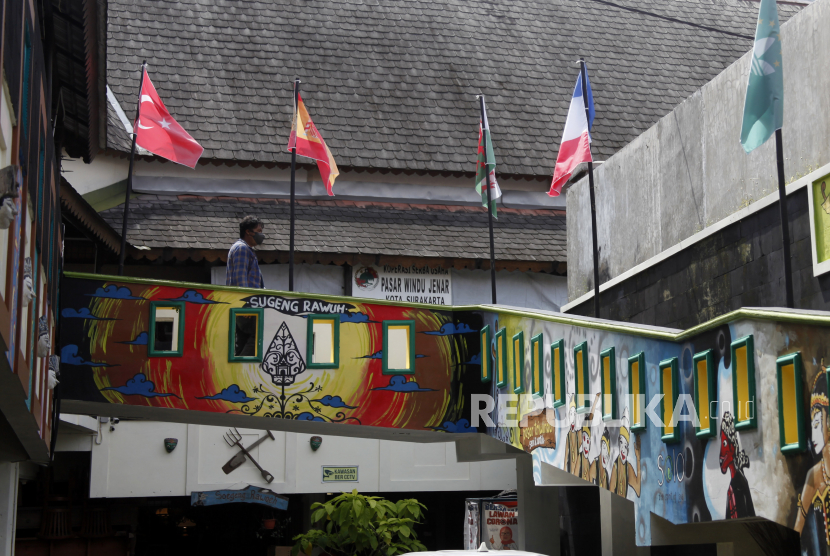 Pengunjung melintas di dekat bendera negara-negara anggota Forum G20 yang terpasang di Pasar Antik Triwindu Solo, Jawa Tengah, Selasa (8/3//2022).  