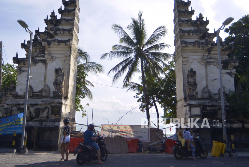 Wisatawan berada di luar kawasan Pantai Kuta yang ditutup sementara di Badung, Bali, Ahad (31/5). Pekerja yang berkutat di sektor pariwisata merupakan pekerja yang paling terdampak karena Covid-19 yang pendapatannya mengalami penurunan. 