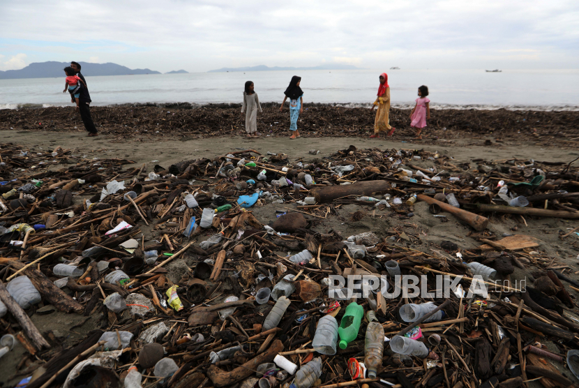 Anak-anak berjalan di antara sampah yang terdampar di pantai Kampung Jawa di Banda Aceh. Ton sampah plastik, sebagian besar botol air dan kemasan makanan yang berasal dari sungai perkotaan, terdampar setelah mencapai laut lepas.