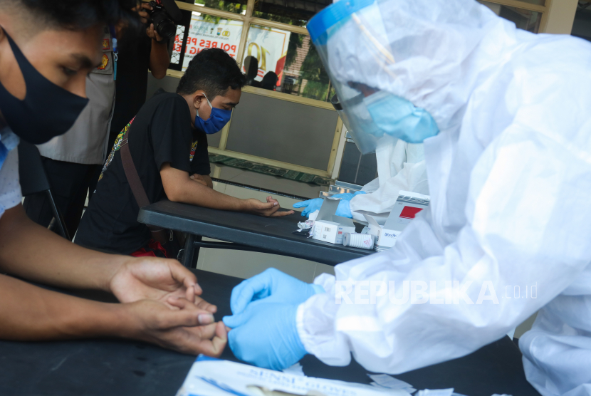 Petugas melakukan pemeriksaan cepat COVID-19 (Rapid Test) kepada warga yang terjaring razia di Polres Pelabuhan Tanjung Perak Surabaya, Jawa Timur, Selasa (5/5/2020). Sejumlah orang yang melanggar pembatasan aktivitas malam hari itu menjalani rapid test COVID-19 serta pemeriksaan lebih lanjut setelah terjaring razia yang digelar oleh pihak kepolisian