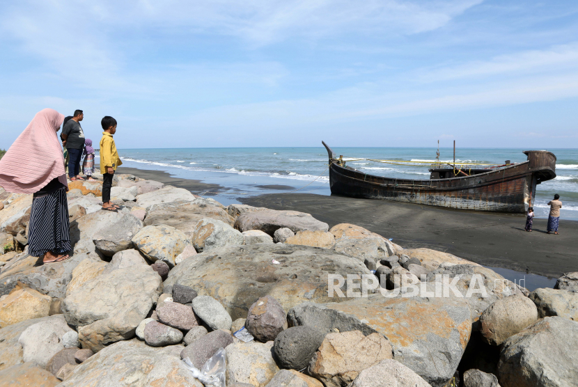 Warga melihat perahu pengungsi Rohingya yang terdampar di pantai Pidie, Provinsi Aceh pada 28 Desember 2022. 